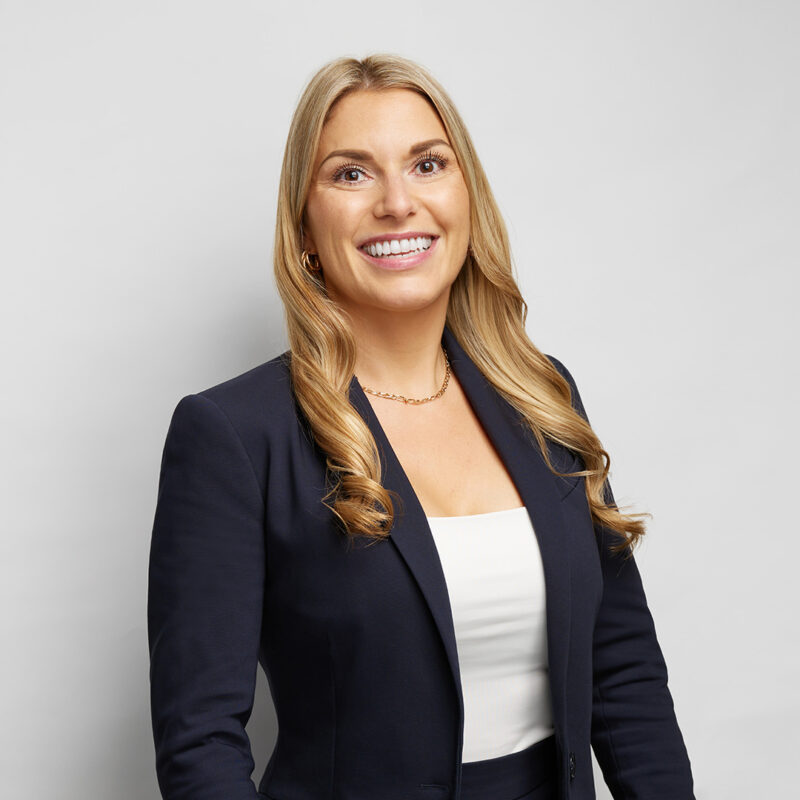 Montreal-corporate-headshot-on-location-team-light-grey-background-female-blonde-navy-suit